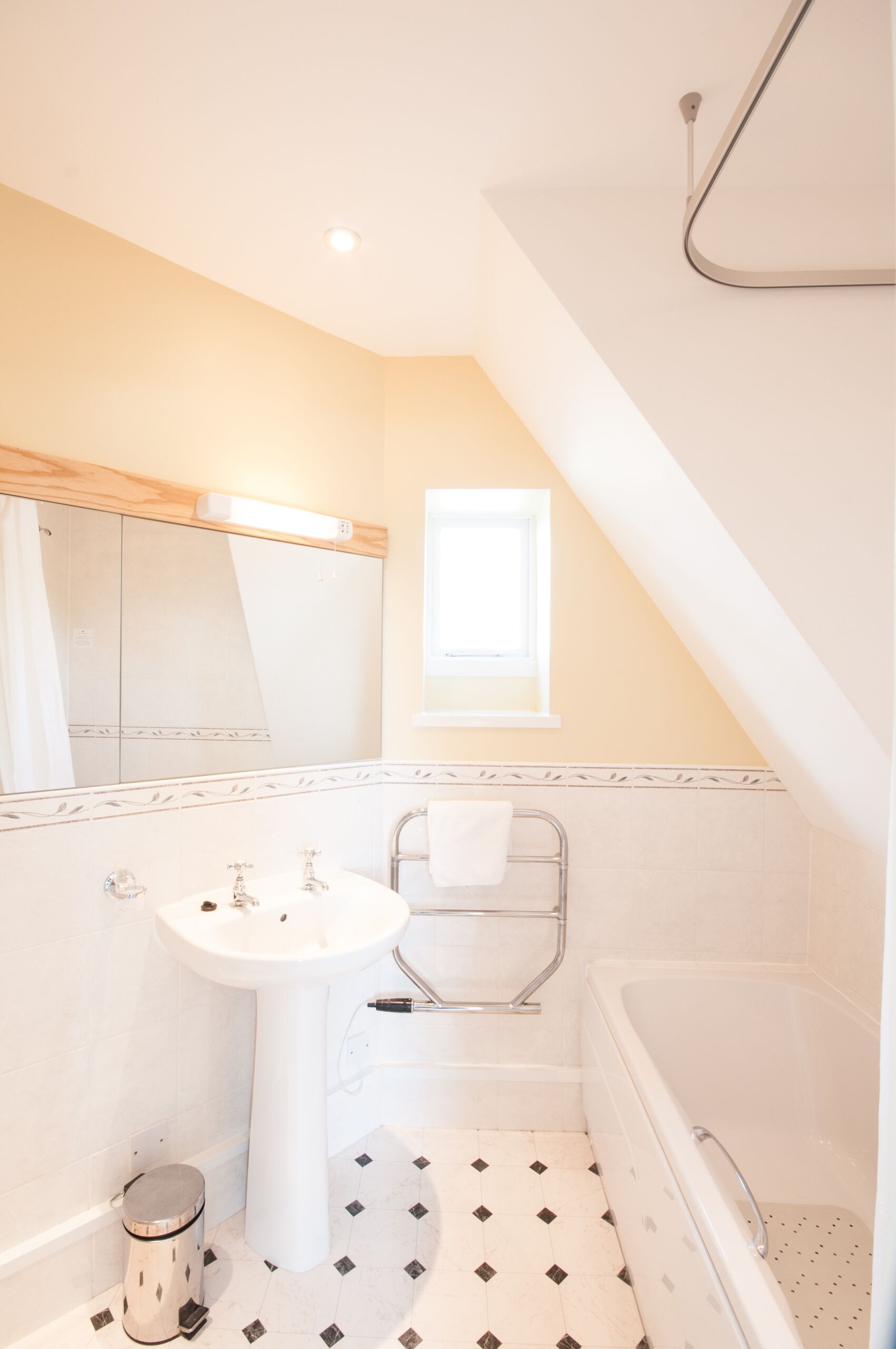 A bathroom with a white sink, a bathtub, and a shower. There is a window above the bathtub and a towel rack next to it.
