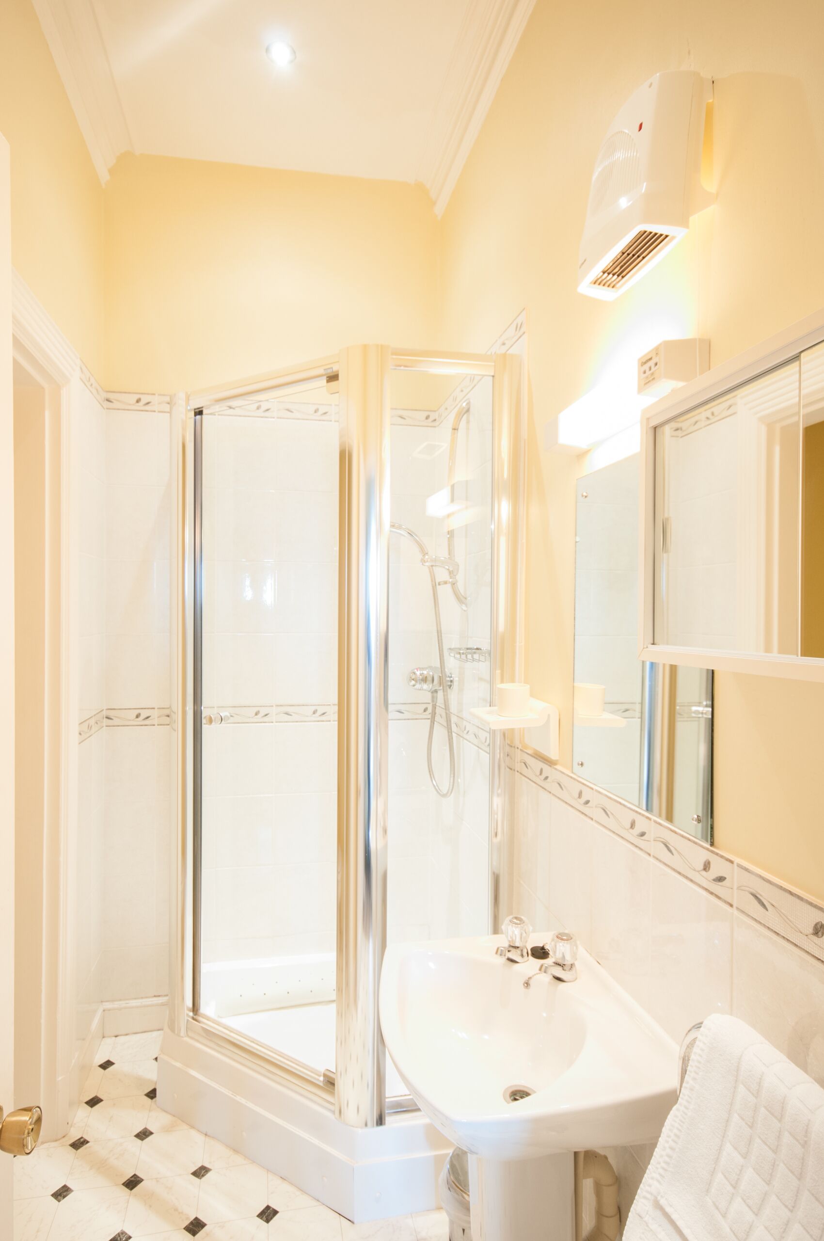 A bathroom with a glass-enclosed shower, a sink, and a mirror.