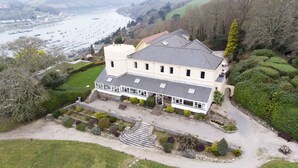 Une grande maison à deux étages, dotée d’un vaste jardin devant et offrant une vue sur la mer.