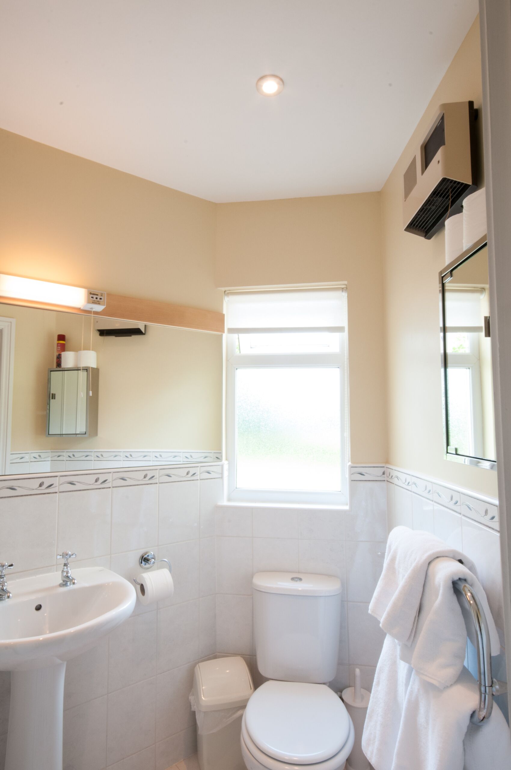 A bathroom with a sink, toilet, and a window.