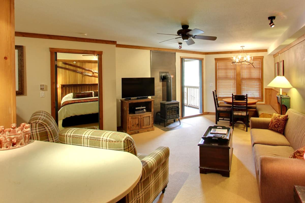 A cozy living room with a television, fireplace, dining area, and a ceiling fan.