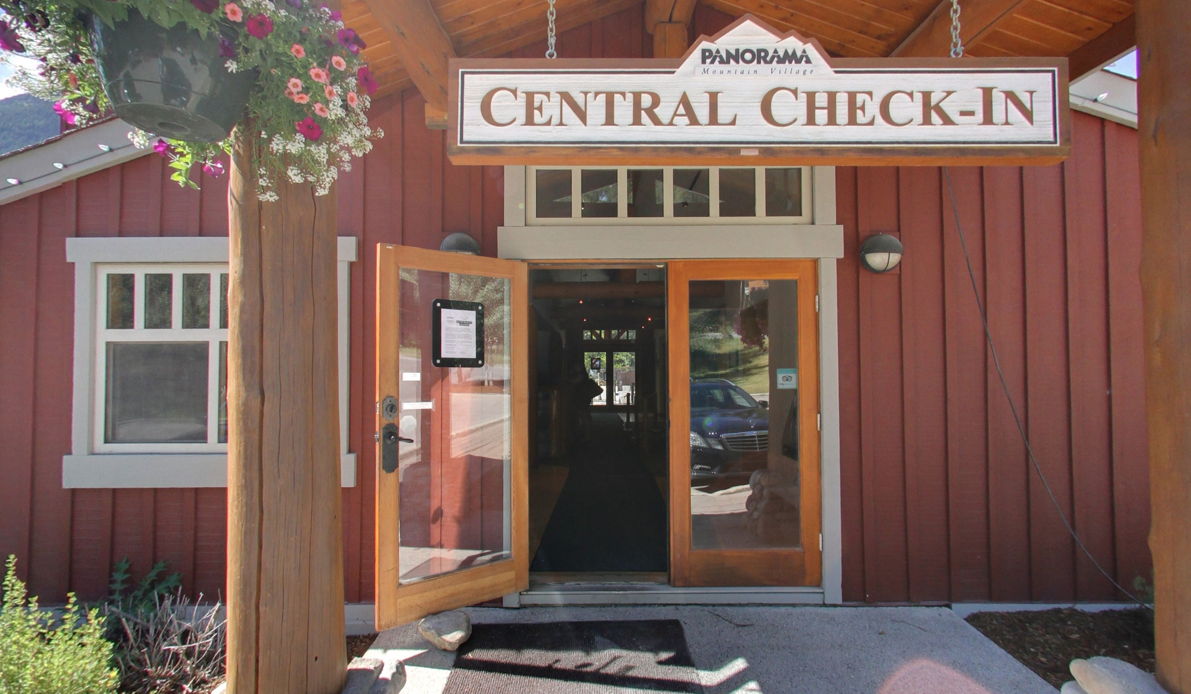 A wooden building with a sign reading "CENTRAL CHECK-IN" and a hanging flower basket.