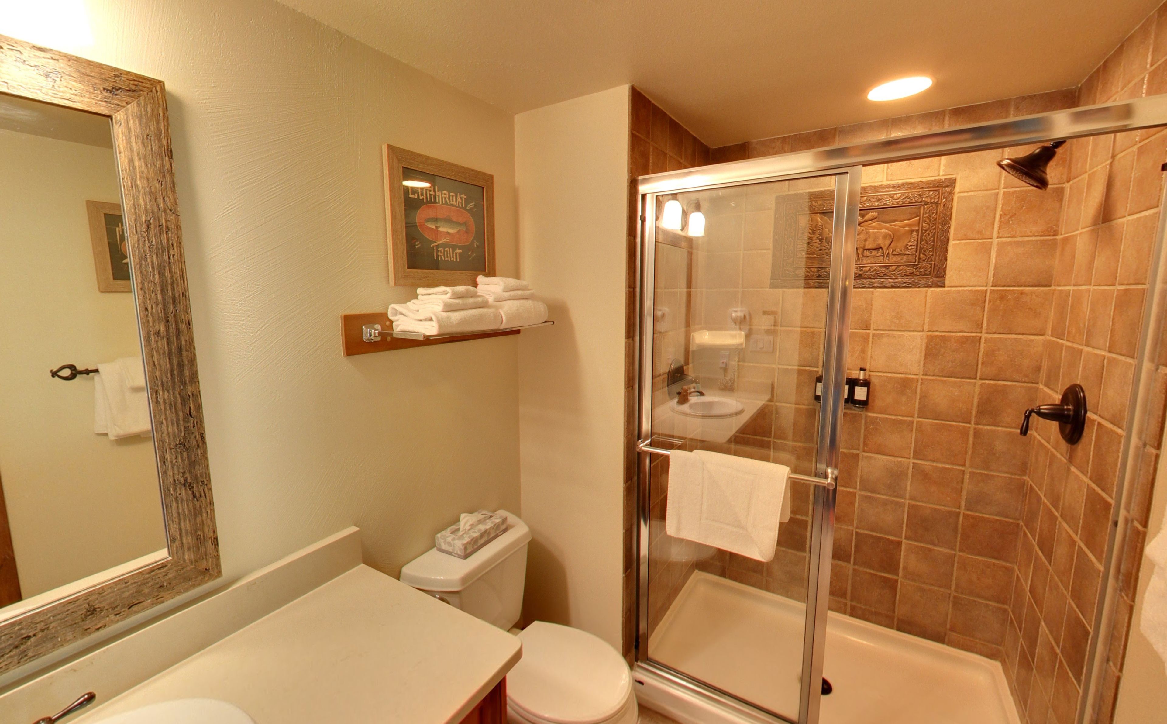 A bathroom with a glass-enclosed shower, a toilet, and a sink.