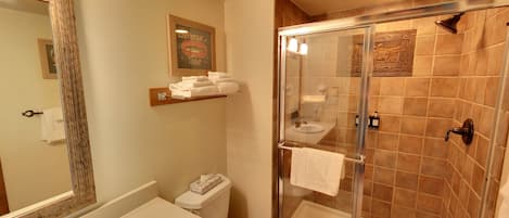 A bathroom with a glass-enclosed shower, a toilet, and a sink.