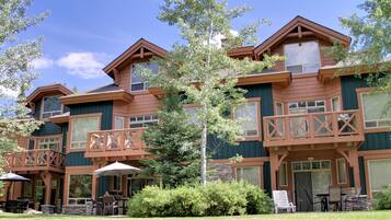 A multi-story building with balconies, outdoor seating, and a stone facade.