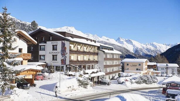 A hotel with a sign reading "HOTEL ALPENHOF" in a snowy mountain area with clear skies. - Gasthof Alpenhof (Mariastein)