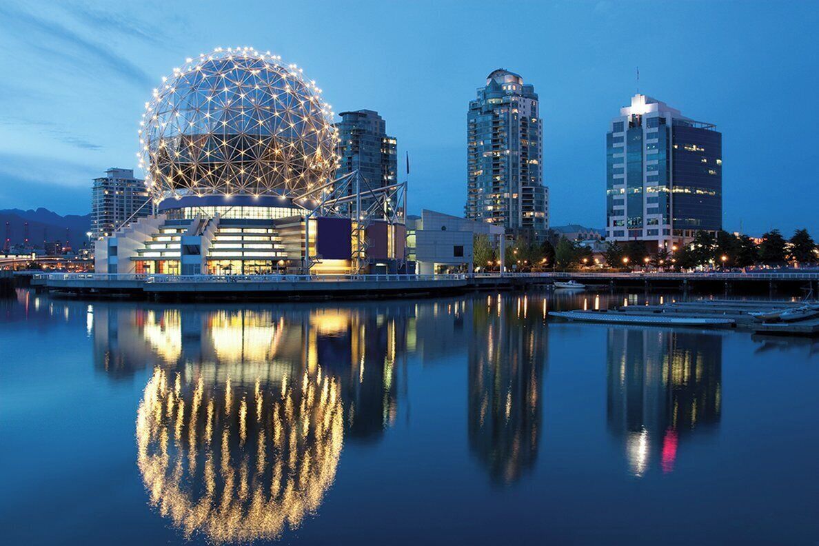 A waterfront cityscape with a large spherical building reflecting on the water, surrounded by modern high-rise buildings.