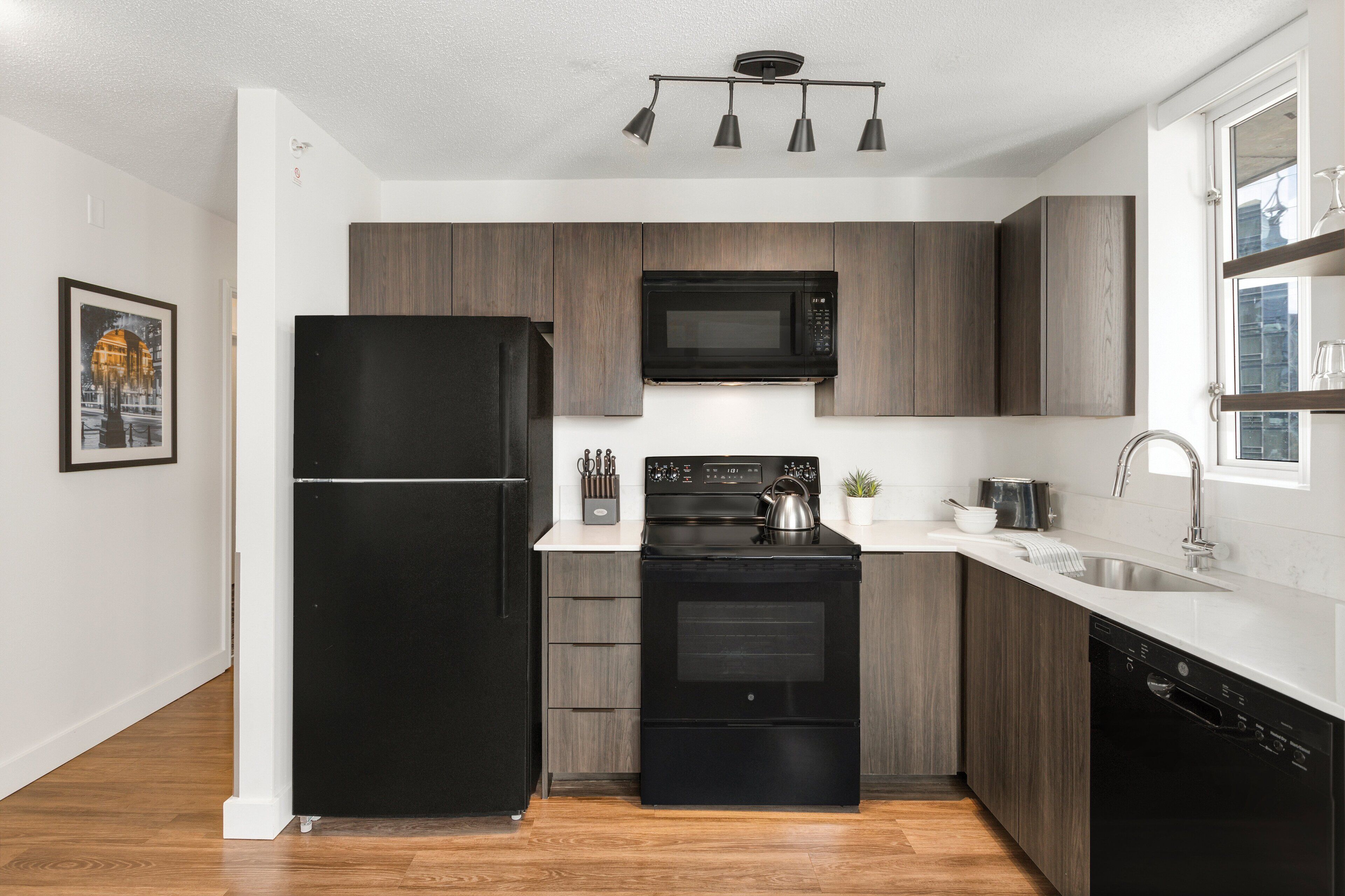 Una cocina moderna con un refrigerador negro, microondas, estufa y lavavajillas.