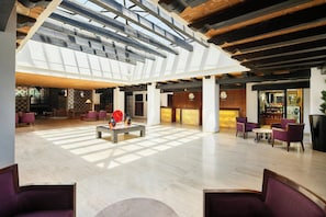 Tilava aula, jossa on korkea katto, vastaanottotiski ja oleskelualueita.