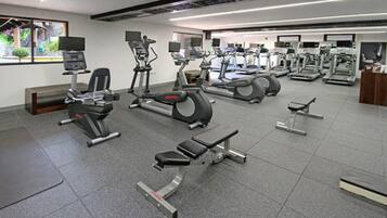 Academia com diversos equipamentos de exercício, incluindo esteiras, bicicletas ergométricas e aparelhos de musculação.
