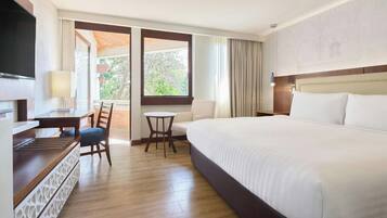 Habitación de hotel con cama, escritorio, silla, televisor y ventana con vistas.