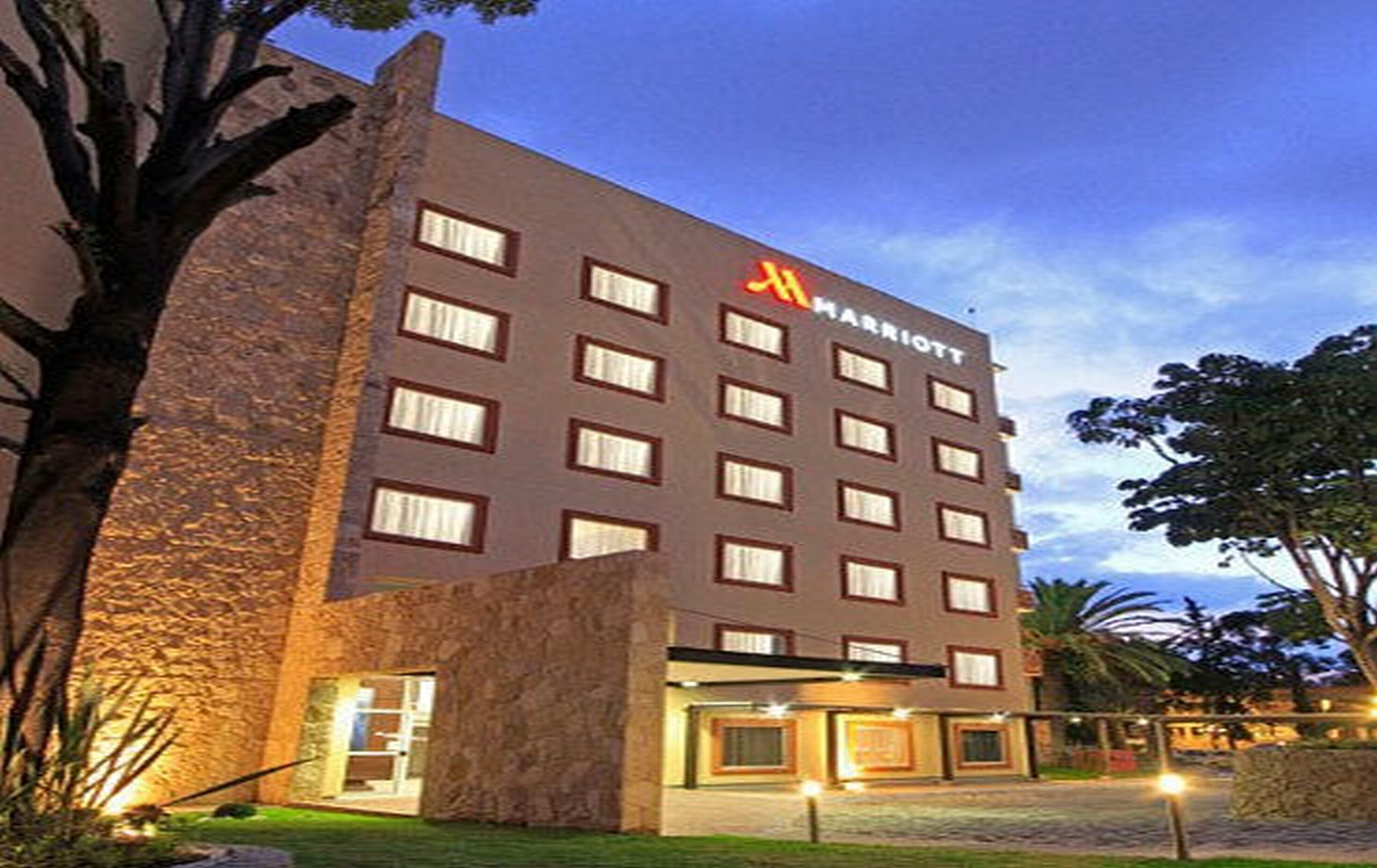 Um hotel com várias andares, fachada de pedra, diversas janelas e entrada visível.
