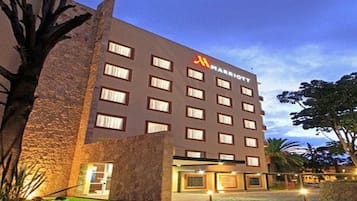 Um hotel com várias andares, fachada de pedra, diversas janelas e entrada visível.