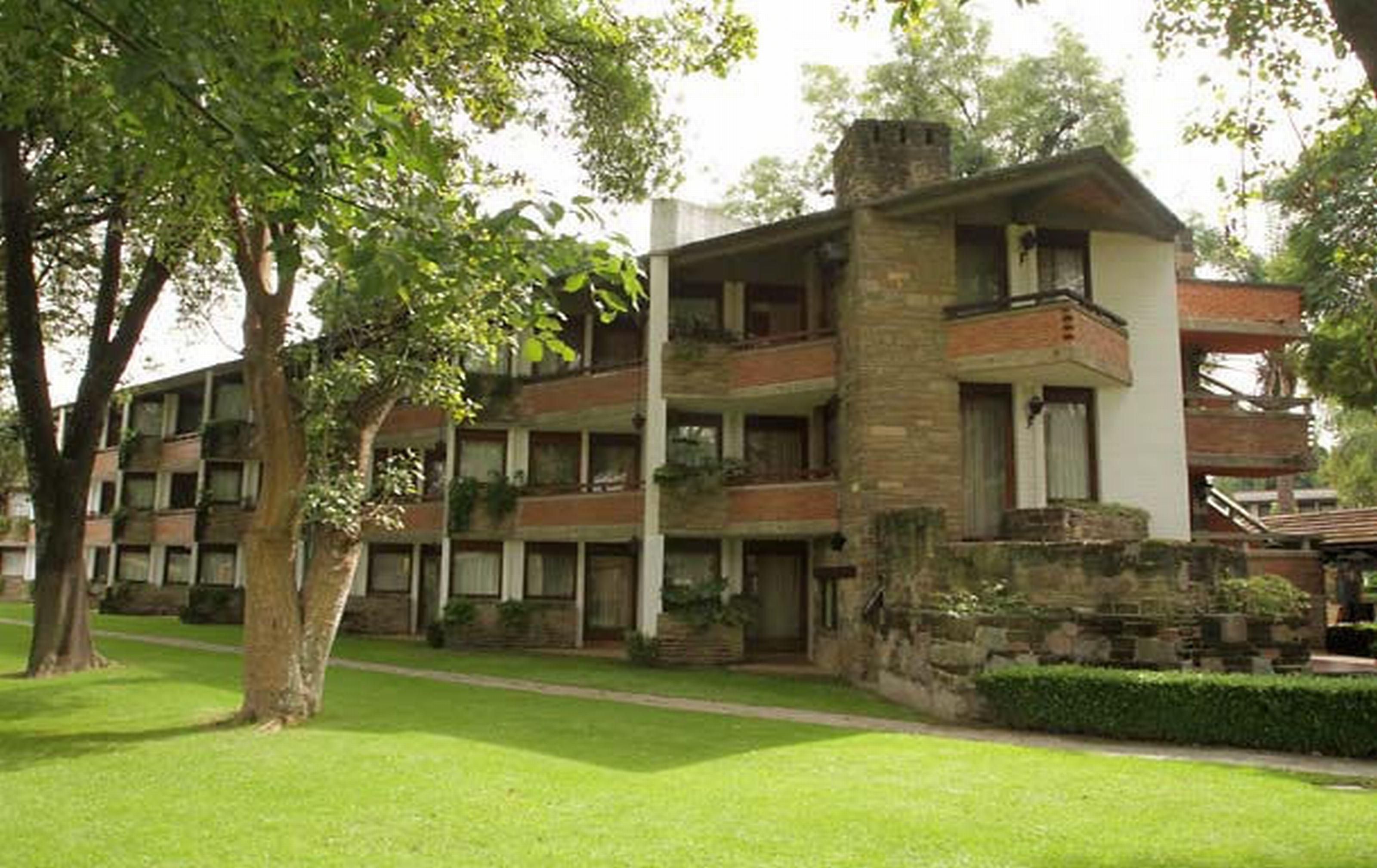 Un edificio de varios pisos con fachada de piedra, balcones y un césped cuidado.