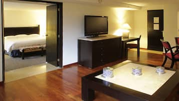 Ein Hotelzimmer mit einem Bett, einem Fernseher auf einem Tisch, einem Schreibtisch mit einer Lampe und einem Sessel.