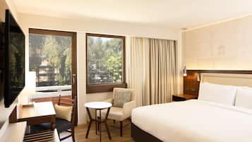 Ein Hotelzimmer mit einem Bett, einem Schreibtisch, einem Sessel, einem kleinen Tisch und einem Fernseher.