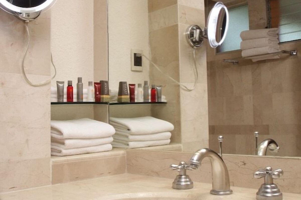 Une salle de bain avec un lavabo, deux miroirs et un porte-serviettes.