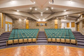 A conference room with tiered seating, stone walls, and a wooden floor.
