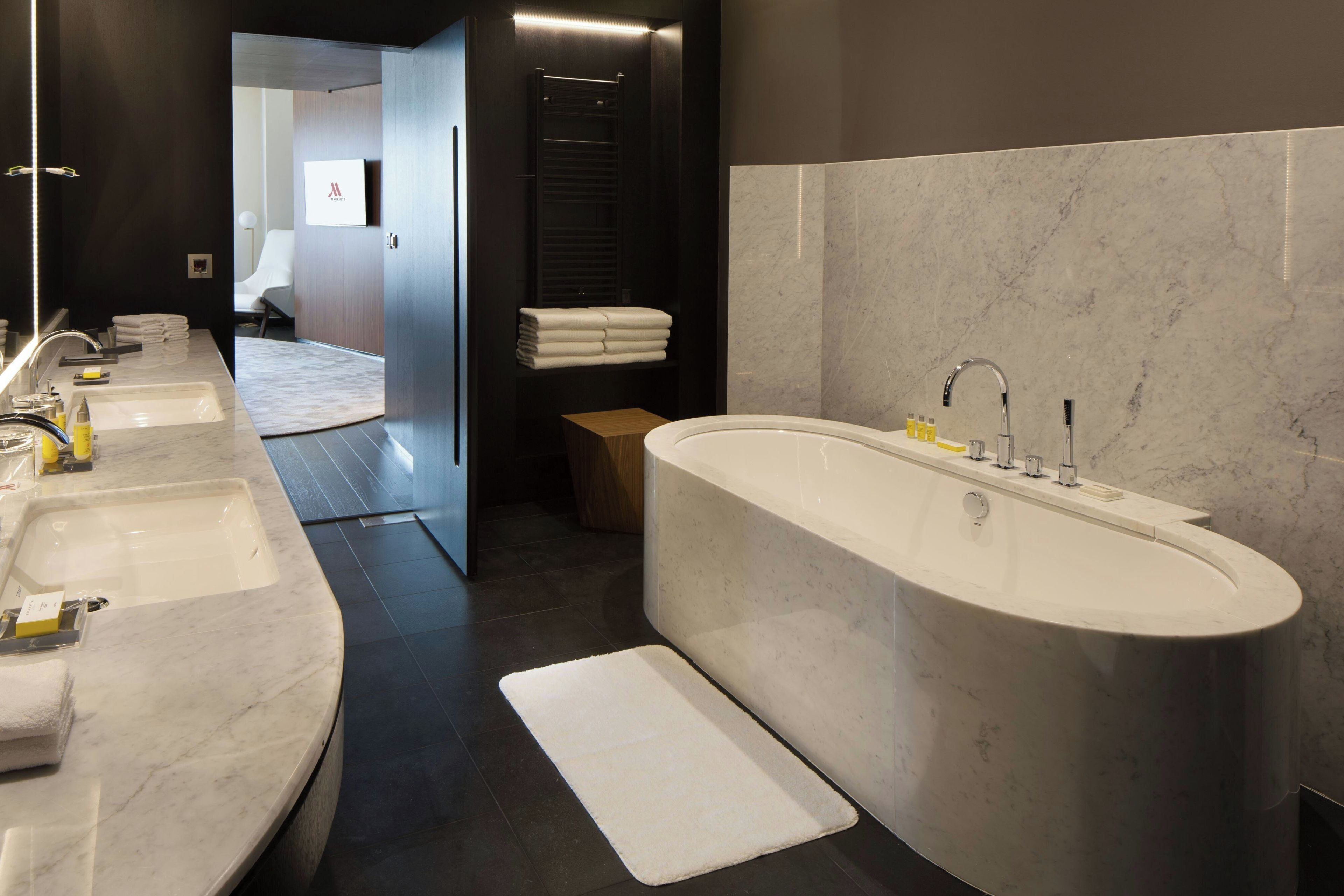 Une salle de bain moderne dotée d’une grande baignoire, d’un meuble-lavabo à deux vasques et d’une douche à l’italienne.