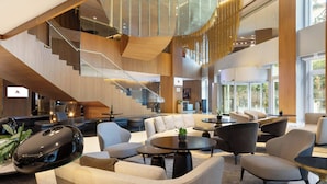 Eine großzügige Lobby mit einer modernen Treppe, gemütlichen Sitzbereichen und großen Fenstern mit Blick.