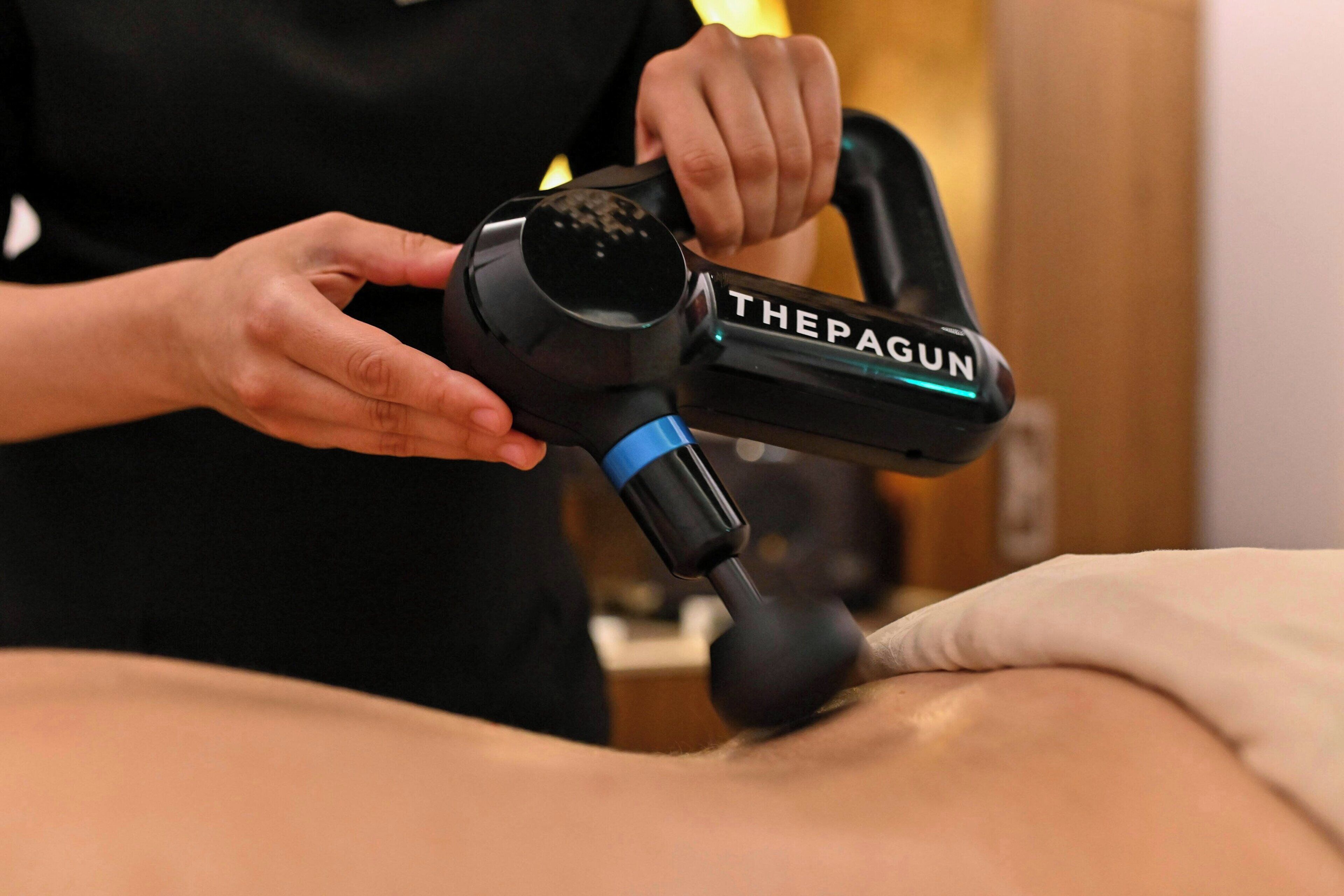 A person using a massage gun on another person's back.