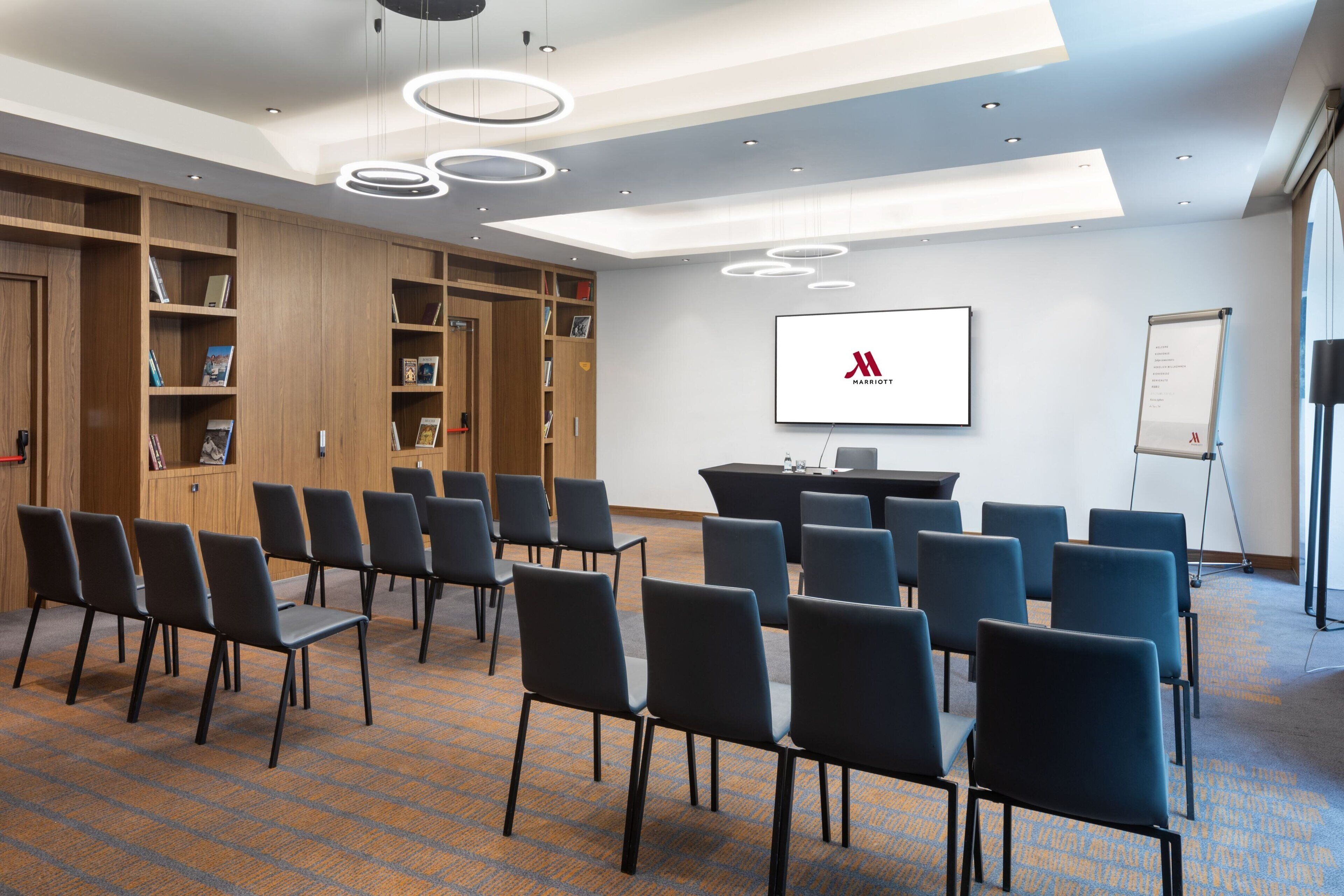 Ein Konferenzraum mit einer Whiteboard, einer Projektionsleinwand und einem Präsentationstisch.