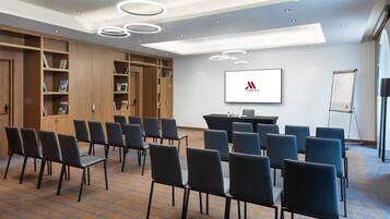 Una sala de conferències amb pissarra, pantalla de projector i un escenari per a presentacions.
