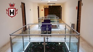 Un vestíbulo de hotel con barandilla de vidrio, mostrador de recepción y escalera decorada con motivos florales.