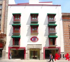 Een gebouw met een witte gevel, groene balkons en een rood logo.