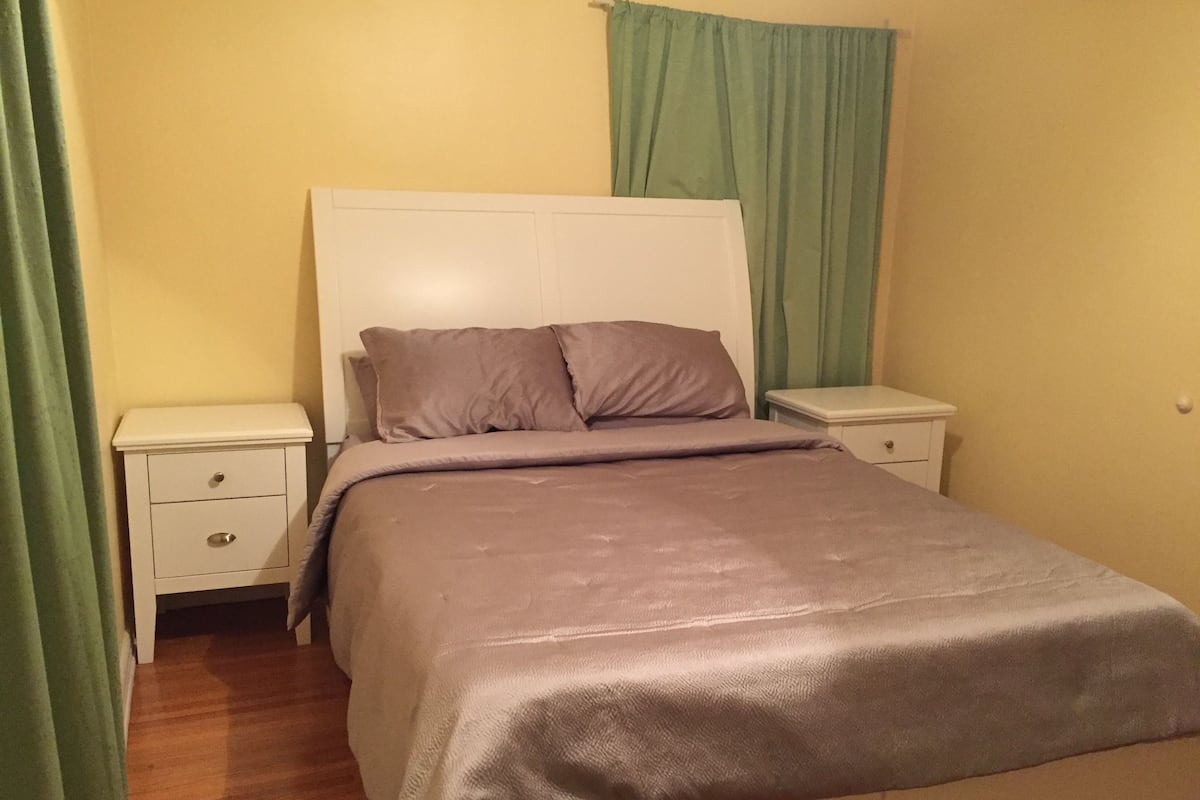 Un dormitorio con una cama, dos mesitas de noche y una mesita auxiliar.