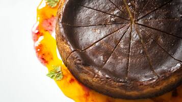 Primer plano de un postre de chocolate con acabado brillante, adornado con una ramita de perejil.