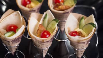 Four food cones with vegetables and a cherry on top.