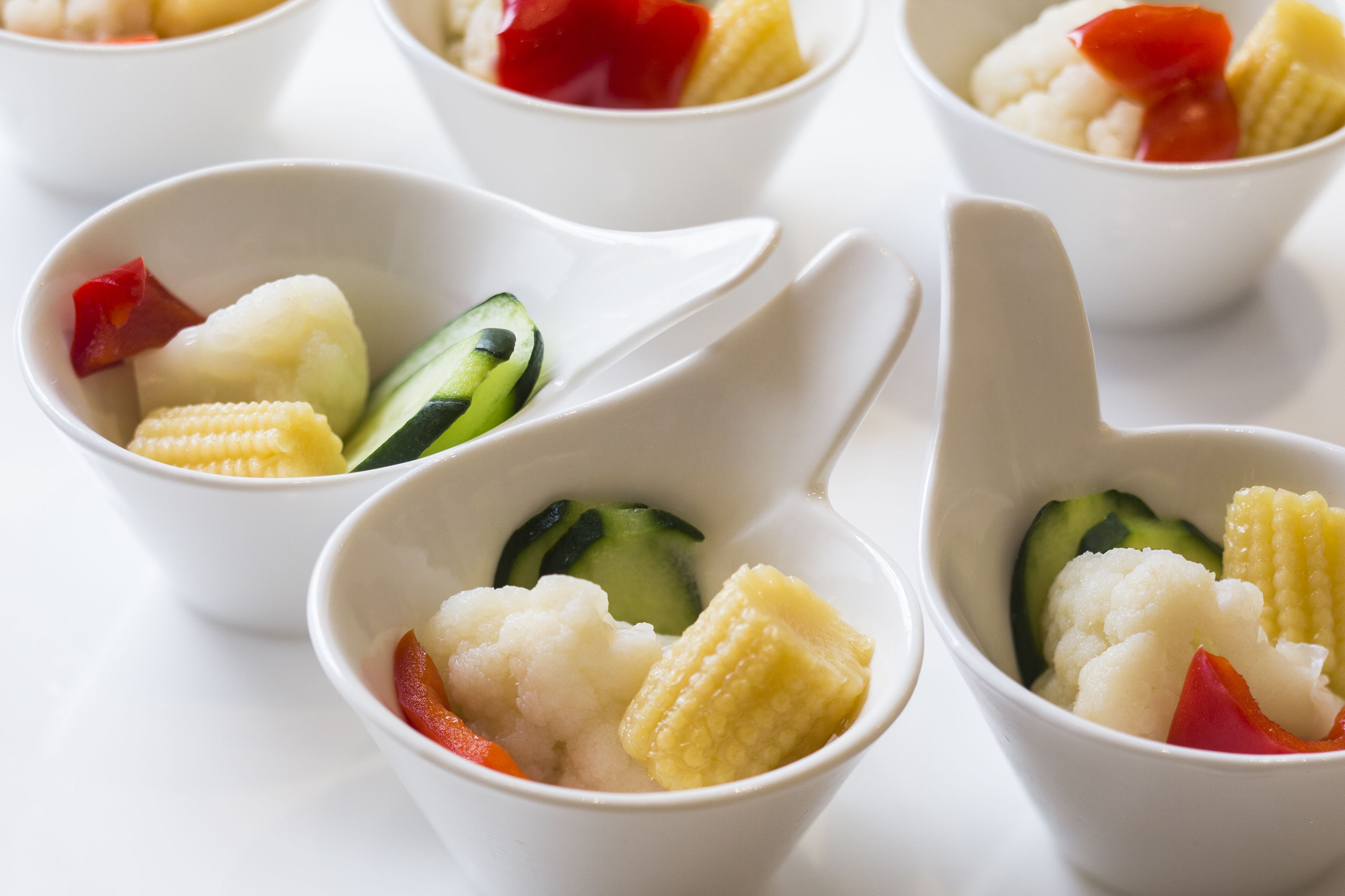 Una serie de tazones blancos con diferentes verduras.