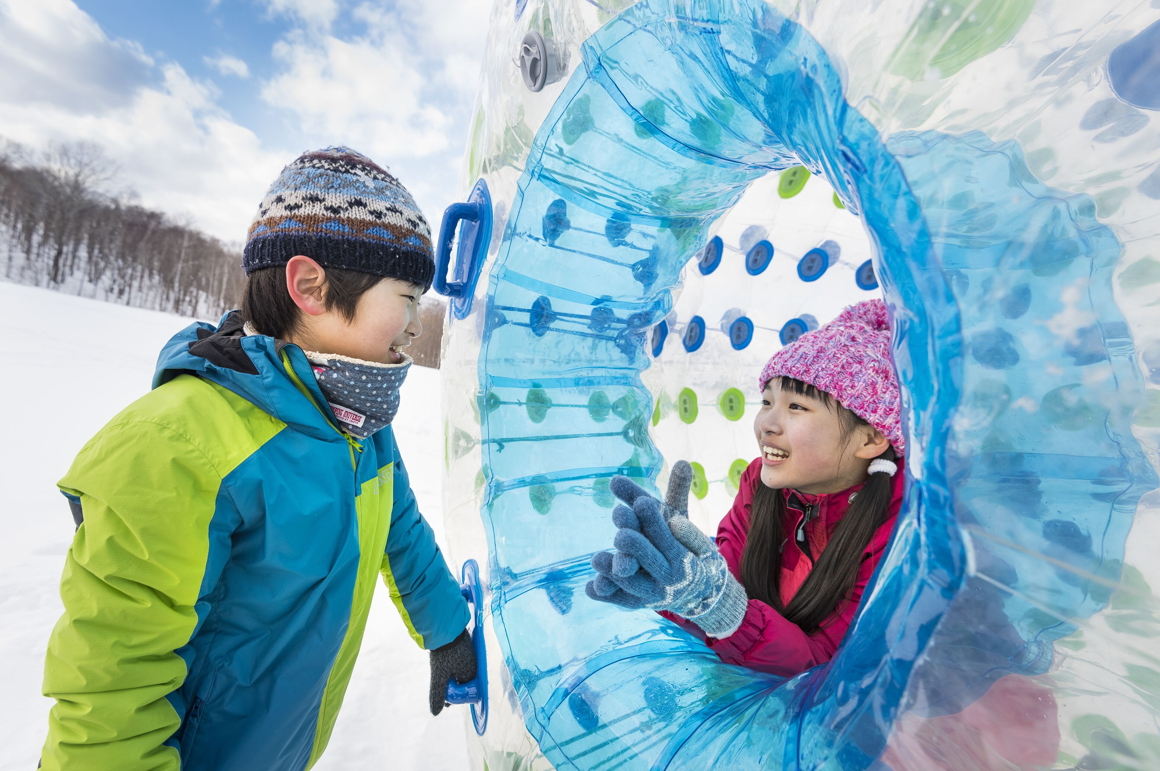 Two children interacting with a transparent ice sculpture.