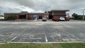 A parking lot with a building labeled "AMERICAS" and a sign for "AMERICA'S BEST BASKETBALL." - Americas Best Value Inn & Suites North Port (North Port)