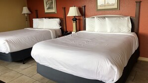 Une chambre d’hôtel avec deux lits, des murs de couleur beige et deux tables de chevet avec des lampes.