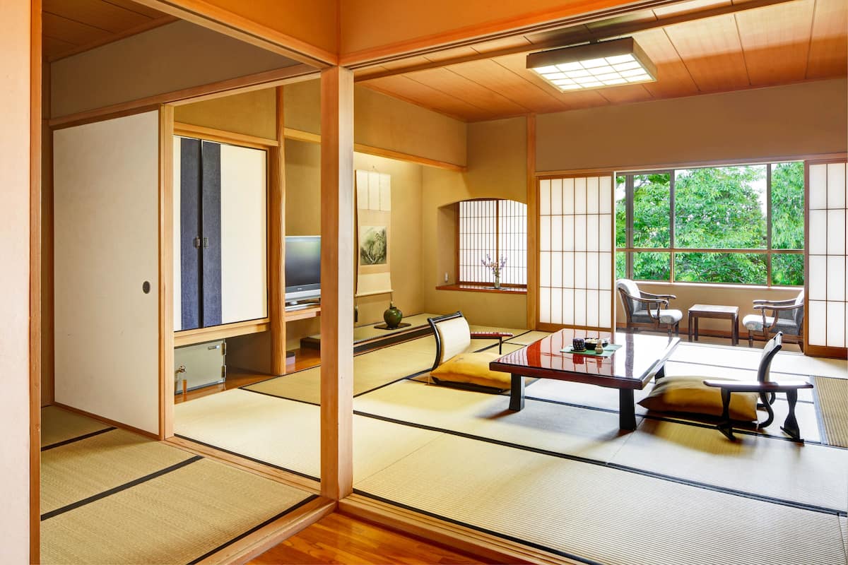 A traditional Japanese room with tatami flooring, a low table with cushions, and sliding doors.