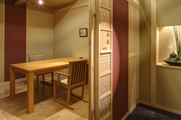 Una mesa de comedor de madera con sillas, un cuadro pequeño en la pared y un panel decorativo de madera con diseño de celosía.