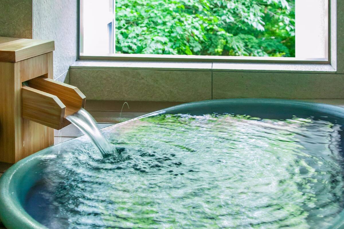 A wooden water feature with a clear view of a window and greenery outside.