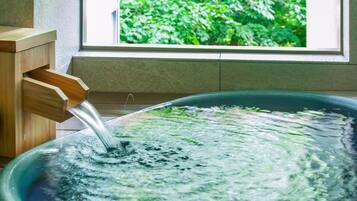 A wooden water feature with a clear view of a window and greenery outside.