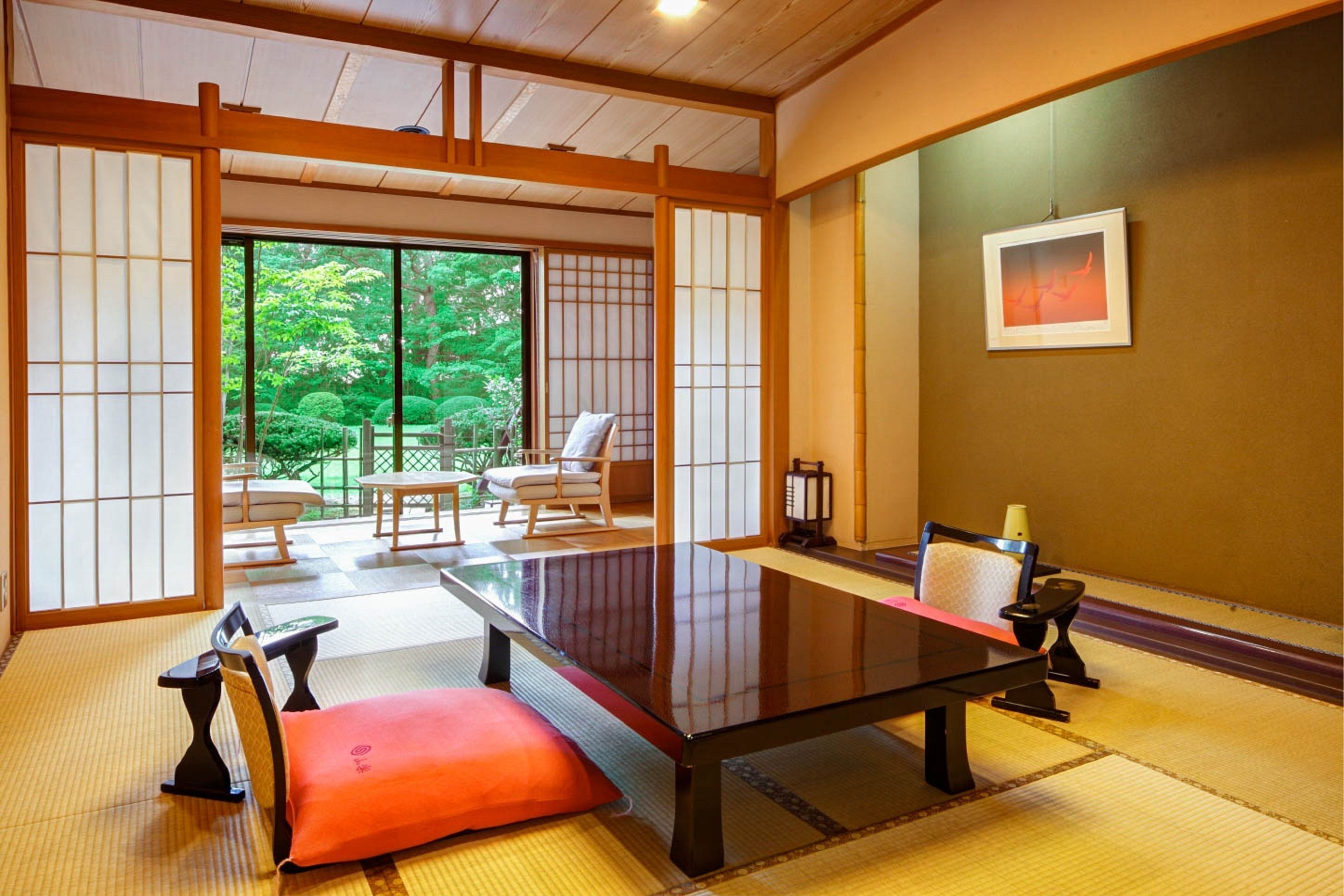 Una habitación japonesa tradicional con suelo de tatami, una mesa baja y puertas correderas que dan a un jardín.