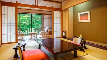 Una habitación japonesa tradicional con suelo de tatami, una mesa baja y puertas correderas que dan a un jardín.