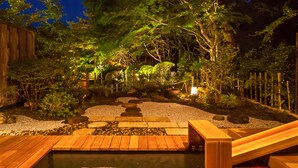 A wooden deck with a small pond, surrounded by rocks and plants, and a wooden fence in a garden setting. - Nasu Onsen Sanraku (Nasu)