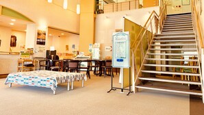 A spacious lobby with a reception desk, seating area, and a staircase leading to an upper level.