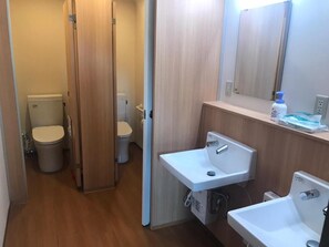 A bathroom with two toilets, a sink, and a mirror. - Hotel Daisen Shirogane (Daisen)