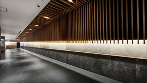 A modern hotel lobby with a long reception desk, dark tiled flooring, and a wooden slatted ceiling design. - Daiwa Roynet Hotel Kyoto Ekimae PREMIER (Kyoto)