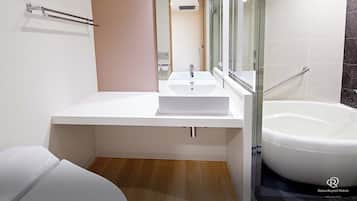 Un baño moderno con un lavamanos blanco, cabina de ducha de vidrio y piso de madera.