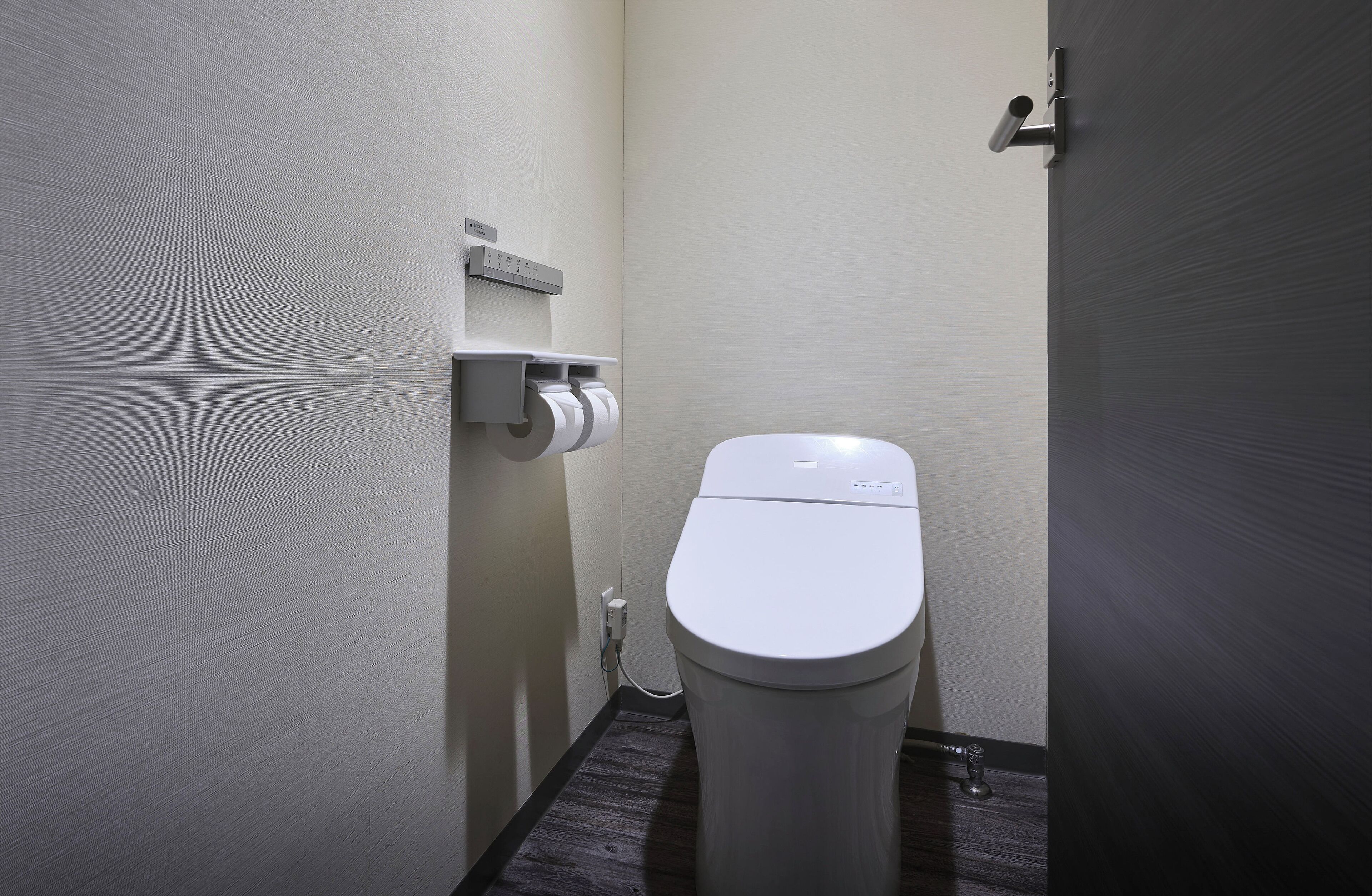 Un baño pequeño y moderno con inodoro, dispensador de toallas de papel y secador de manos.