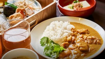 A meal with white rice, curry, and a glass of tea on a wooden table.