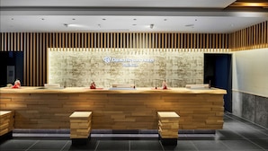 A reception desk with a wooden finish, a wall with vertical wooden slats, and a sign for Daiwa Roynet Hotel Premier. - Daiwa Roynet Hotel Kyoto Ekimae PREMIER (Kyoto)